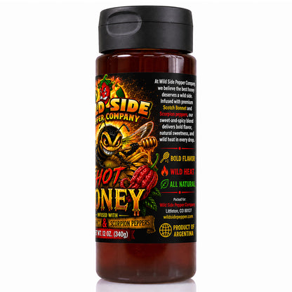 A bottle of Wild Side Pepper Company Hot Honey, featuring a black lid and a black label with illustrations of a bee, honeycomb, and red chili peppers, set against a plain white background.