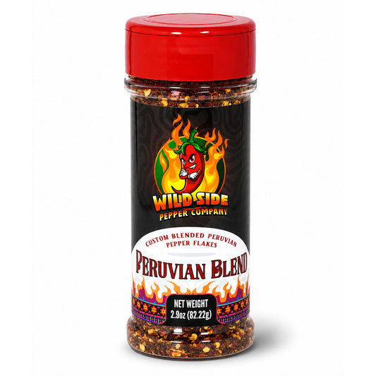A clear plastic jar of Wild Side Pepper Company Peruvian Blend pepper flakes with a bright red lid and a black label featuring a red chili pepper logo, set against a plain white background.