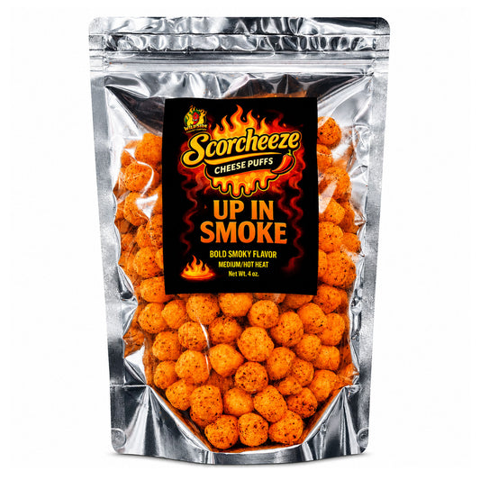 A silver stand-up pouch of Scorchzee Cheese Puffs, featuring a prominent black label with fiery orange and yellow graphics and the text 'UP IN SMOKE'. The clear front of the bag shows numerous round, orange-brown cheese puffs seasoned with specks of seasoning.